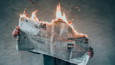 person holding a newspaper that is on fire